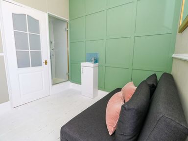 A bathroom with a shower, sink, and sofa at The Old Post Office in Weymouth