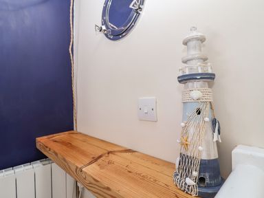 A wooden shelf with a lighthouse decoration and a wall switch at Admiral Cottage in Blaxhall near Snape Suffolk