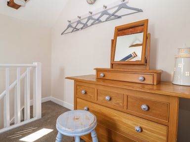 A hallway area with a wooden dresser with mirror above and a blue stool at Admiral Cottage in Blaxhall near Snape Suffolk