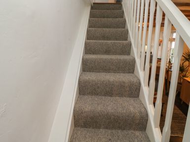 A carpeted staircase with white railing inside a house at Mulberry Tree in Appledore