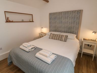 A bedroom with a bed neatly made with folded towels on top and two bedside tables with lamps at Mulberry Tree in Appledore