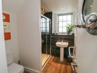 A bathroom with a shower, pedestal sink, toilet, window, and plant on windowsill at Mulberry Tree in Appledore
