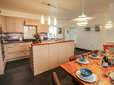 A kitchen with beige cabinets and a dining table set with blue bowls and glasses at Lands House in Appledore