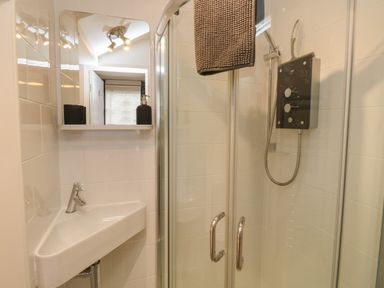 A bathroom with a corner sink and a glass shower enclosure at Lands House in Appledore