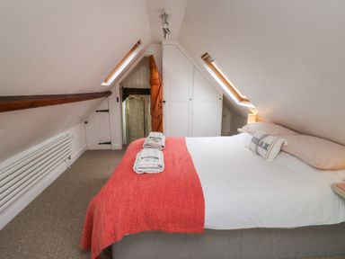 An attic bedroom with a double bed and red throw blanket at Lands House in Appledore