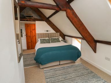 A bedroom with a double bed under exposed wooden beams and a wooden door at Lands House in Appledore
