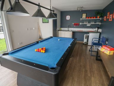 A game room with a blue pool table and a kitchenette area at Lands House in Appledore