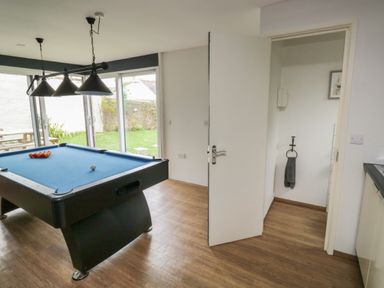 A room with a blue pool table and a large window opening to a garden at Lands House in Appledore