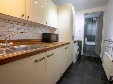 A kitchen with a sink microwave and washing machine visible at Lands House in Appledore