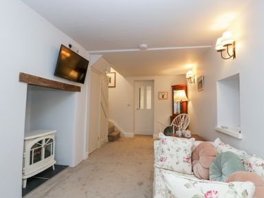 A living room with a floral sofa and TV mounted above a fireplace at The Old Thatch in Porlock