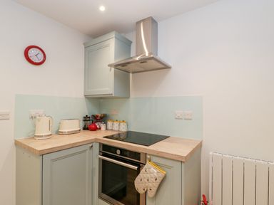 A kitchen corner with a stove oven kettle toaster clock and utensils at The Old Thatch in Porlock