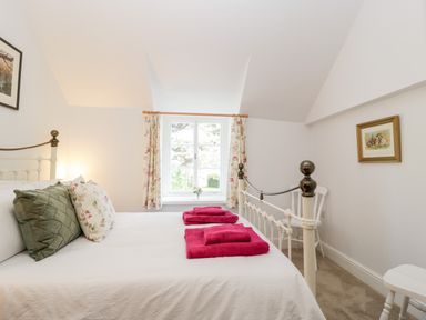 A bedroom with a bed with pink towels and pillows by a window at The Old Thatch in Porlock