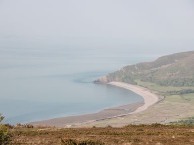 A coastline with a sandy beach and grassy hills at The Old Thatch in Porlock