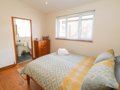 A bedroom with a bed towel on top and a doorway leading to a bathroom at Gloccamaura in Bovey Tracey