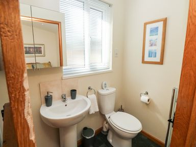 A bathroom with a sink toilet mirror window and framed pictures at Gloccamaura in Bovey Tracey