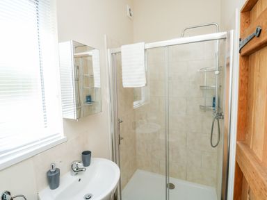A bathroom with a shower enclosure sink mirror and wooden door at Gloccamaura in Bovey Tracey