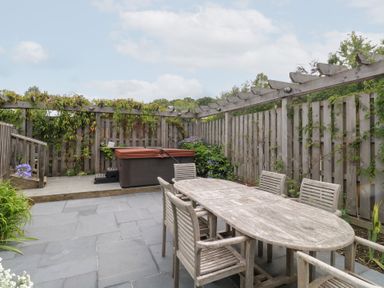 A garden with a dining table and hot tub at Gloccamaura in Bovey Tracey