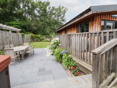An outdoor patio area with a wooden table and chairs at Gloccamaura in Bovey Tracey