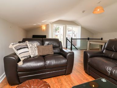 A living room with leather sofas wooden floor and a pool table at Hazelwood Lodge in High Bickington