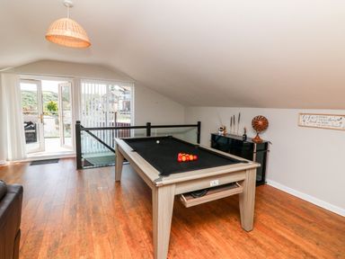 A room with a pool table near glass doors and a black cabinet with decorative items at Hazelwood Lodge in High Bickington