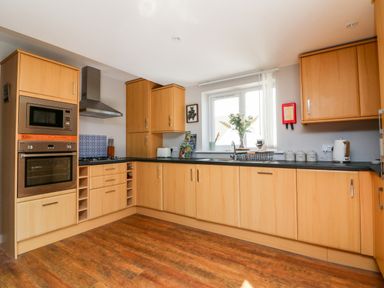 A kitchen with wooden cabinets oven microwave stove and window at Hazelwood Lodge in High Bickington