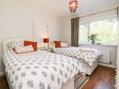 A bedroom with two single beds a window and a bedside table with a lamp at Hazelwood Lodge in High Bickington
