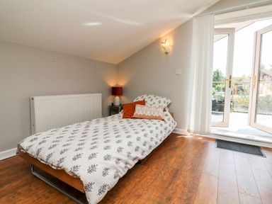 A bedroom with a single bed next to a radiator and glass doors leading outside at Hazelwood Lodge in High Bickington