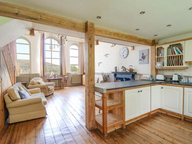 An open-plan kitchen and living area with wooden floors and beams at St Marks School House in Nant-Glas near Rhayader