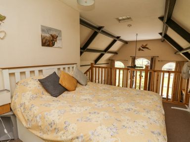 A bedroom with a bed covered in yellow floral bedding and pillows at St Marks School House Nant-Glas near Rhayader