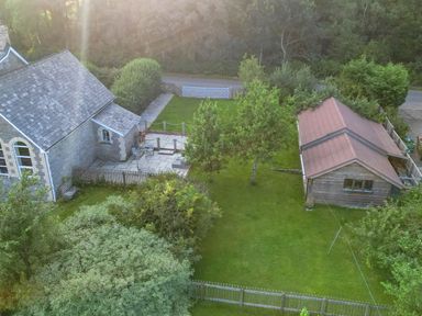 A garden with trees lawn and a shed next to a stone building at St Marks School House in Nant-Glas near Rhayader
