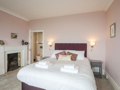 A bedroom with a bed and pillows towels and nightstands near a fireplace at Llys Owen in Criccieth