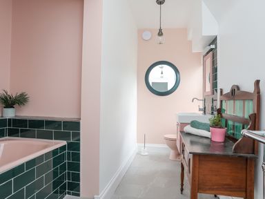 A bathroom with a bathtub with dark green tiles and pink walls at Llys Owen in Criccieth