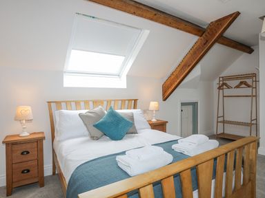 A bedroom with a wooden bed and bedside tables under a skylight at Llys Owen in Criccieth