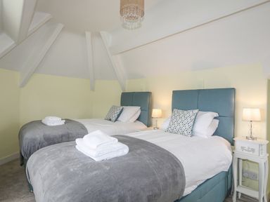 A bedroom with two single beds gray blankets white pillows and blue headboards at Llys Owen in Criccieth