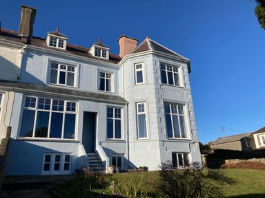 Exterior view of a two story house with multiple windows and a small staircase leading to a door at Llys Owen in Criccieth