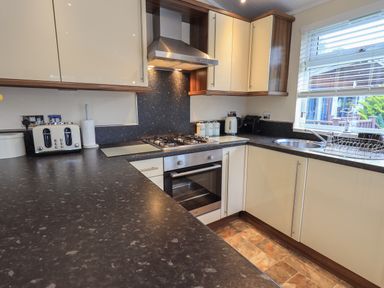A kitchen with a stove oven sink toaster kettle and window at Hill Top Lodge in Bowness 65 White Cross Bay