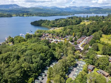 An aerial view of a lakeside village with boats on the water surrounded by trees at Hill Top Lodge in Bowness 65 White Cross Bay