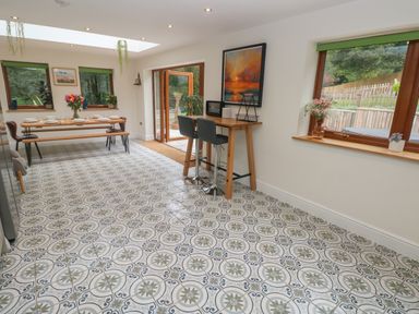 A dining area with a wooden table set with plates and glasses and a high wooden table with two stools at Rudbaxton Water in Rudbaxton near Haverfordwest