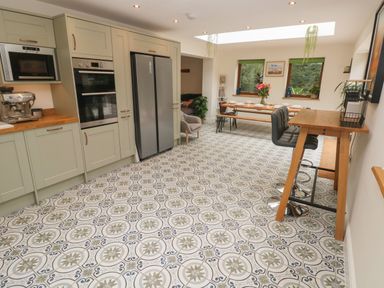 A kitchen with patterned tiled floor cabinets refrigerator and dining table with chairs at Rudbaxton Water Rudbaxton near Haverfordwest
