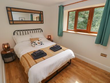 A bedroom with a double bed bedside tables and a window with green curtains at Rudbaxton Water in Rudbaxton near Haverfordwest