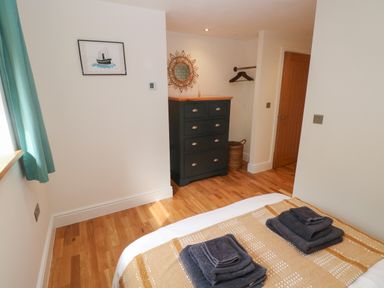 A bedroom with towels on a bed a black chest of drawers a round mirror and green curtains at Rudbaxton Water Rudbaxton near Haverfordwest