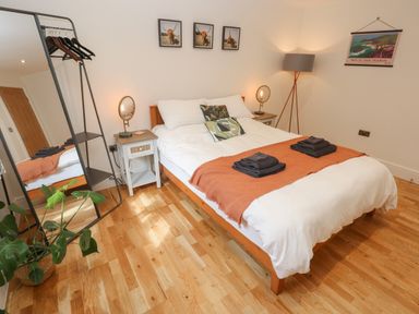 A bedroom with a double bed bedside tables a standing mirror a floor lamp and wall art at Rudbaxton Water Rudbaxton near Haverfordwest