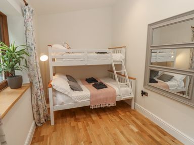 A bedroom with a white bunk bed a plant on a window sill and a wall mirror at Rudbaxton Water Rudbaxton near Haverfordwest