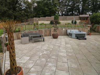 A patio with outdoor furniture a hot tub and potted plants at Rudbaxton Water Rudbaxton near Haverfordwest