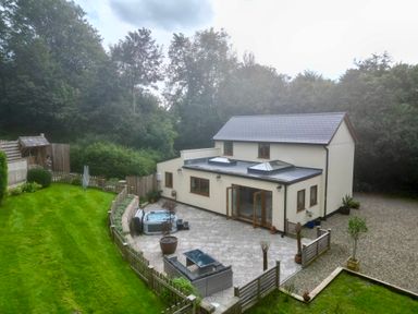 A two-story house with a patio garden lawn seating area and hot tub at Rudbaxton Water Rudbaxton near Haverfordwest