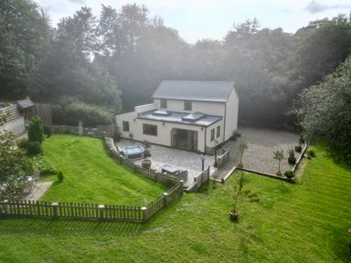 A house with a fenced garden patio and lawn surrounded by trees at Rudbaxton Water in Rudbaxton near Haverfordwest