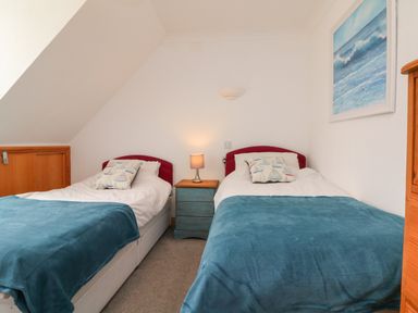 A bedroom with two single beds blue blankets and a nightstand with a lamp at 5 Seymour Villas in Woolacombe