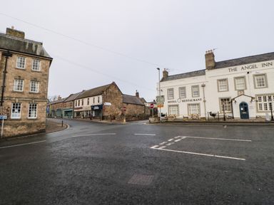 A street intersection with buildings including The Angel Inn hotel and restaurant and stone buildings at Willows in Corbridge