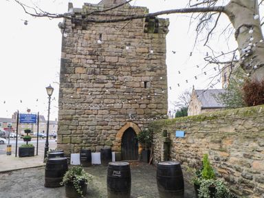 An outdoor area with a stone tower and barrels arranged around it at Willows in Corbridge