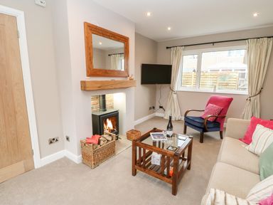 A living room with a fireplace mirror armchair sofa coffee table and window at Willows in Corbridge